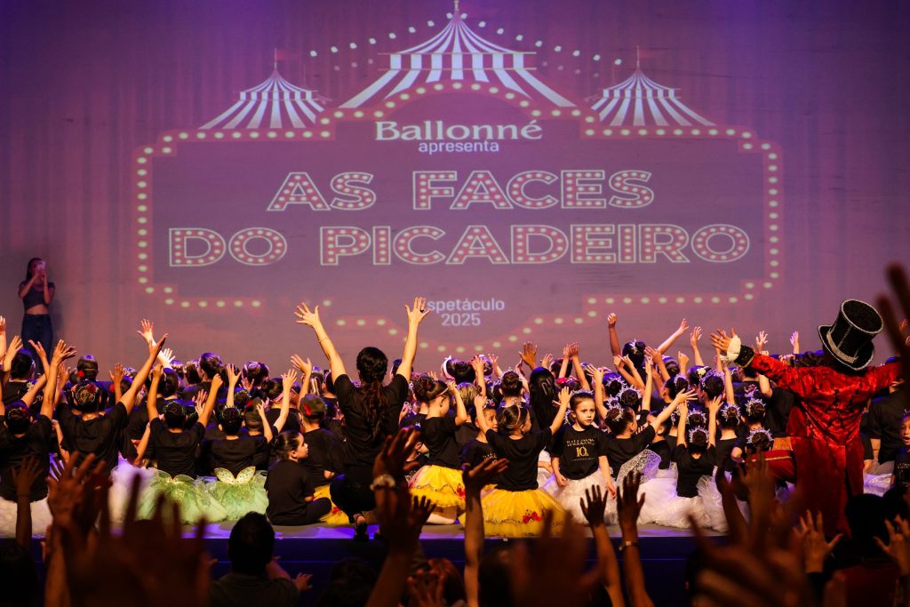 Revelação do tema do espetáculo 2025 “As Faces do Picadeiro” ao final do espetáculo comemorativo “Ballonné é 10!”, com alunos no palco e mestre de cerimônias em destaque.